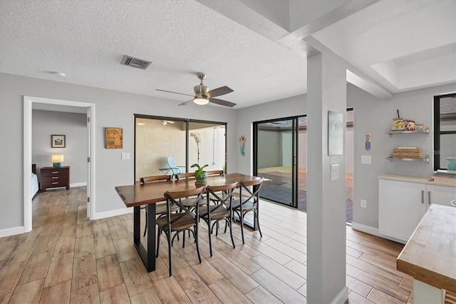 dining room with a textured ceiling, baseboards, visible vents, and wood tiled floor