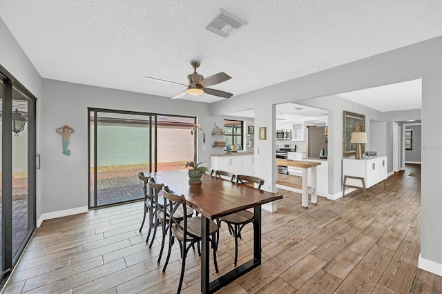 dining area with wood tiled floor, visible vents, ceiling fan, and baseboards