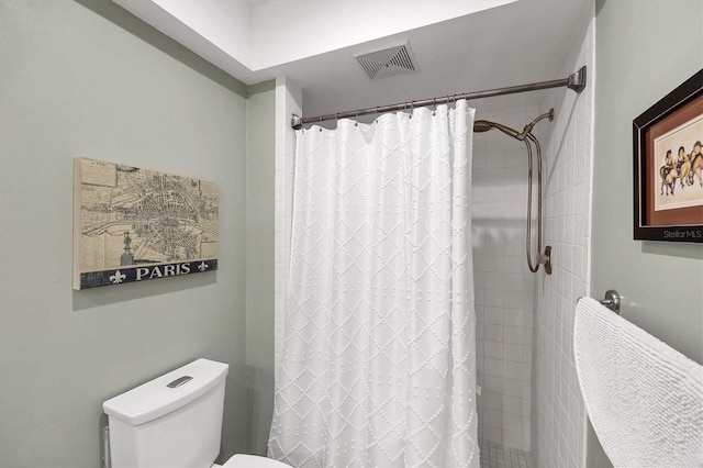 bathroom featuring toilet, a tile shower, and visible vents