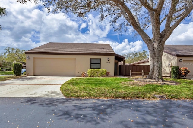 view of front of property with stucco siding, concrete driveway, a front yard, fence, and a garage