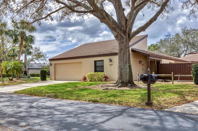 ranch-style house with concrete driveway, an attached garage, fence, a front lawn, and stucco siding