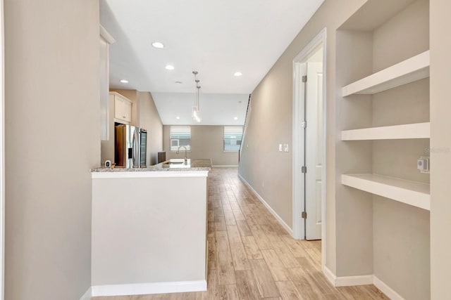 kitchen featuring light wood-type flooring, stainless steel fridge, baseboards, and recessed lighting