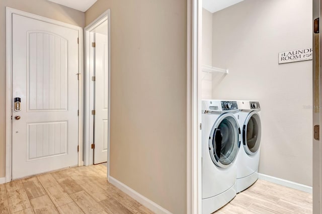 clothes washing area with laundry area, light wood-style flooring, baseboards, and washer and dryer