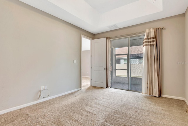 carpeted spare room with a raised ceiling and baseboards