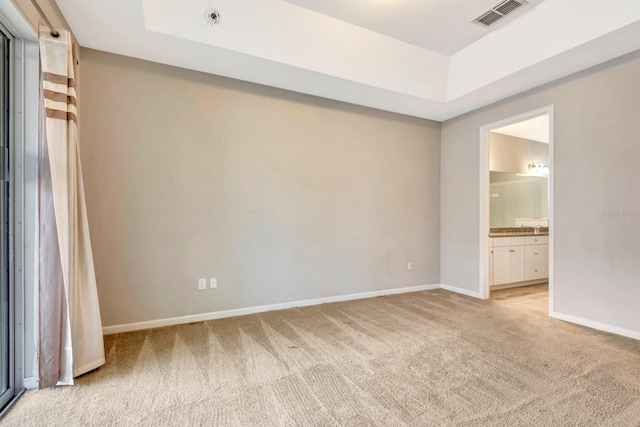 unfurnished room featuring light carpet, baseboards, visible vents, and a tray ceiling