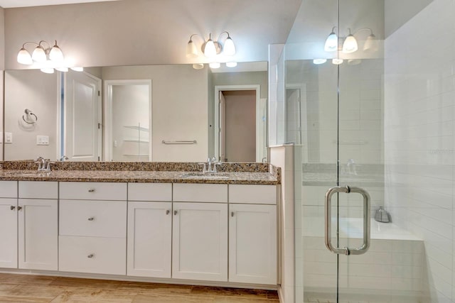 bathroom with double vanity, a shower stall, and a sink