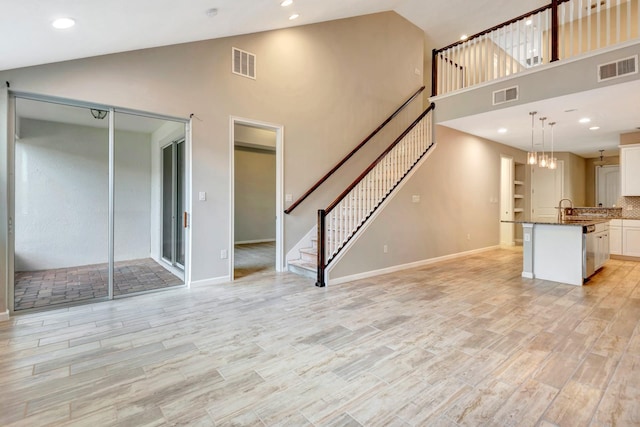 unfurnished living room featuring stairway, light wood-type flooring, and visible vents