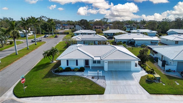 view of front of house featuring a tile roof, concrete driveway, an attached garage, a front yard, and a residential view