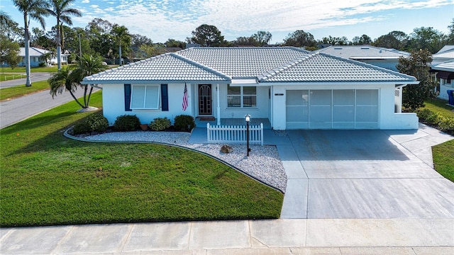 single story home with a garage, a tile roof, concrete driveway, stucco siding, and a front lawn