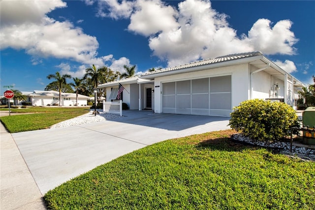 ranch-style home featuring a front lawn, driveway, an attached garage, and stucco siding