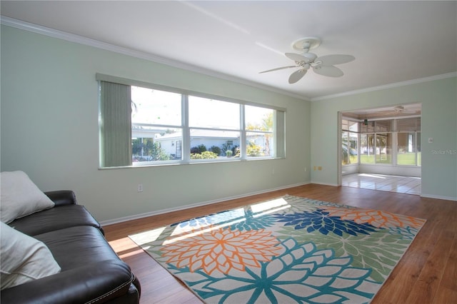 living room with baseboards, ceiling fan, wood finished floors, and crown molding