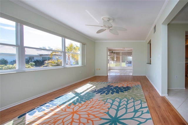 spare room featuring baseboards, visible vents, wood finished floors, and ornamental molding