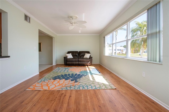 living area with visible vents, crown molding, baseboards, and wood finished floors