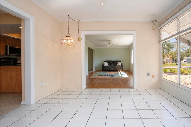 unfurnished dining area featuring ceiling fan, crown molding, and light tile patterned floors