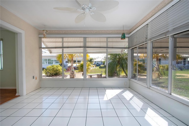 unfurnished sunroom featuring a ceiling fan and a healthy amount of sunlight