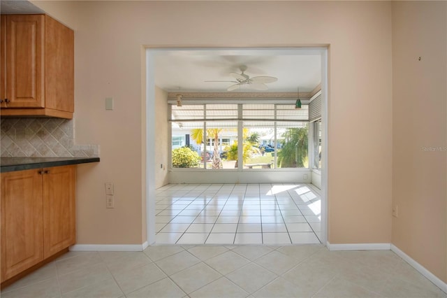 interior space featuring light tile patterned floors, ceiling fan, and baseboards