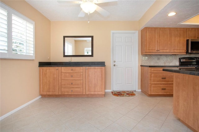 kitchen featuring light tile patterned floors, stainless steel appliances, dark countertops, tasteful backsplash, and baseboards