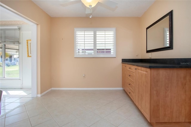 interior space featuring light tile patterned floors, ceiling fan, and baseboards