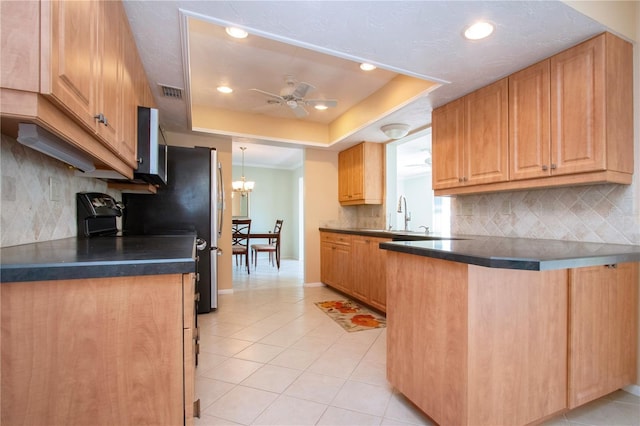 kitchen featuring a peninsula, dark countertops, light tile patterned floors, and a raised ceiling