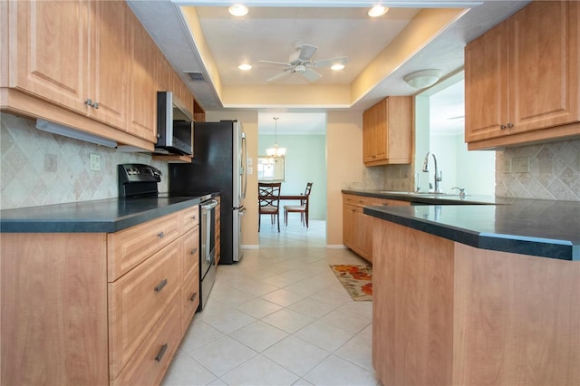 kitchen featuring a tray ceiling, light tile patterned floors, stainless steel appliances, dark countertops, and visible vents