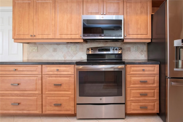 kitchen featuring appliances with stainless steel finishes, dark countertops, backsplash, and light tile patterned flooring