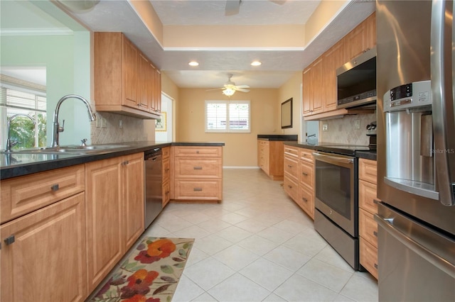 kitchen with stainless steel appliances, dark countertops, a ceiling fan, light tile patterned flooring, and a sink