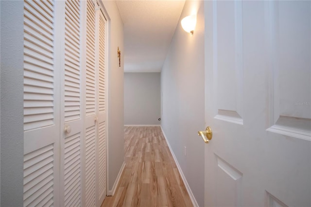 hall featuring light wood-type flooring and baseboards