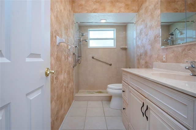 full bathroom with tile patterned flooring, tiled shower, vanity, and toilet