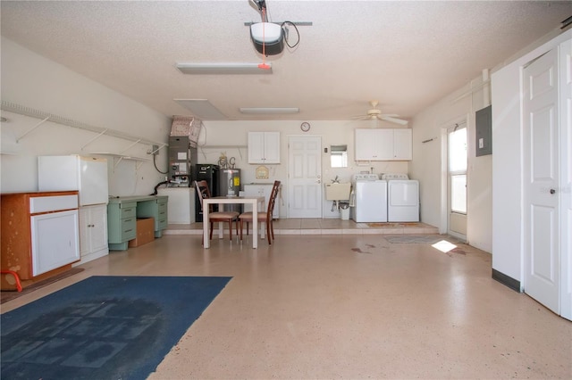 garage featuring a garage door opener, a ceiling fan, electric water heater, a sink, and separate washer and dryer