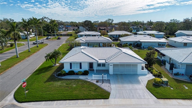 view of front facade with concrete driveway, a garage, a residential view, a tiled roof, and a front lawn