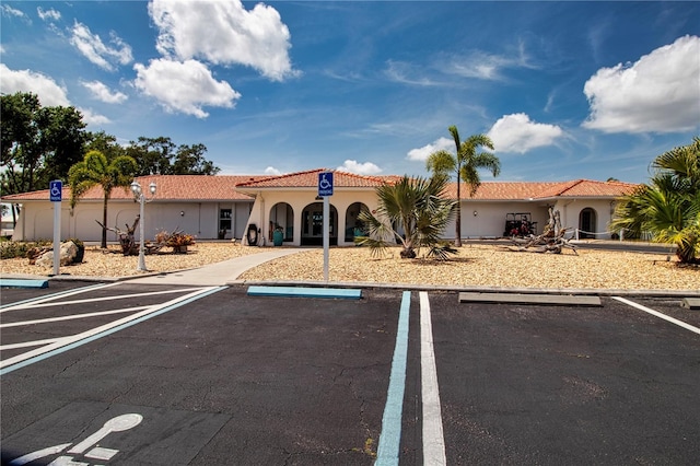 view of front facade featuring uncovered parking, a tiled roof, and stucco siding