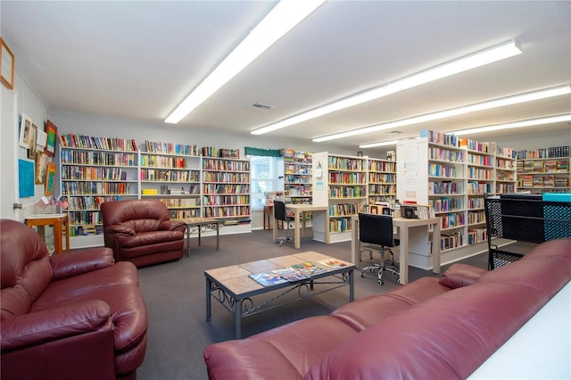 living area featuring wall of books, carpet flooring, and visible vents