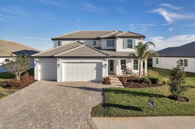 traditional home with a garage, decorative driveway, a front yard, and a tile roof