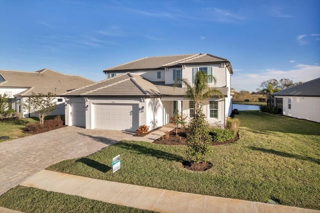 traditional home featuring a tiled roof, decorative driveway, an attached garage, and a front yard