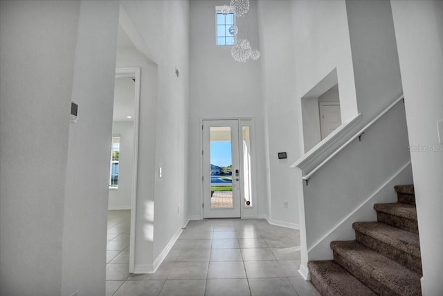 tiled foyer with an inviting chandelier, a high ceiling, baseboards, and a wealth of natural light