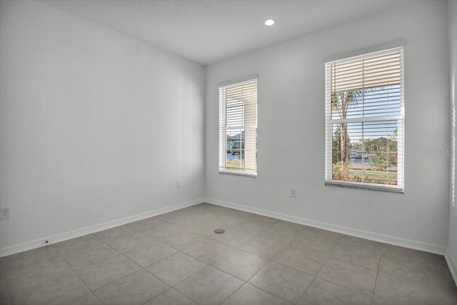 tiled empty room with recessed lighting and baseboards