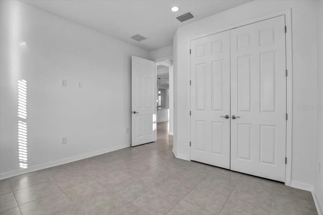 unfurnished bedroom with light tile patterned floors, baseboards, visible vents, and a closet