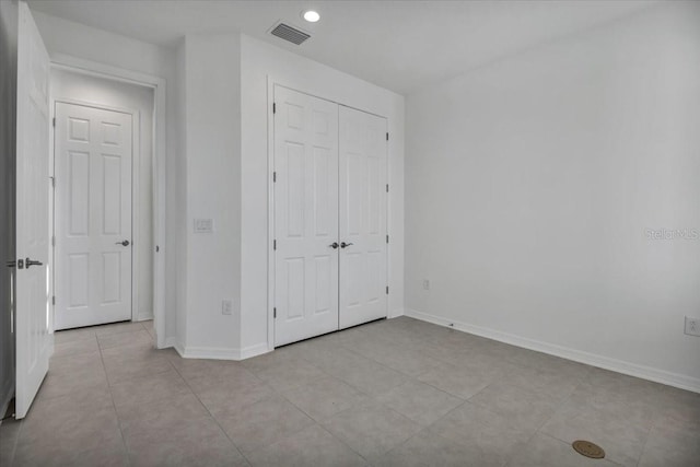 unfurnished bedroom featuring light tile patterned floors, baseboards, visible vents, and a closet