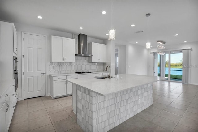 kitchen featuring light tile patterned floors, a sink, light countertops, backsplash, and wall chimney exhaust hood