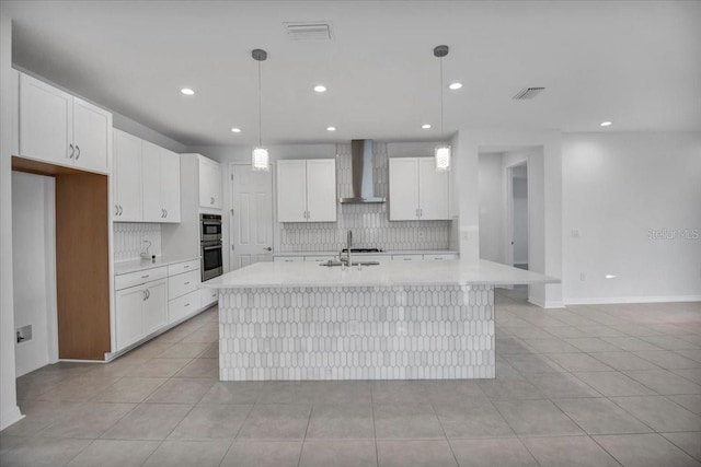 kitchen featuring white cabinetry, wall chimney exhaust hood, and visible vents