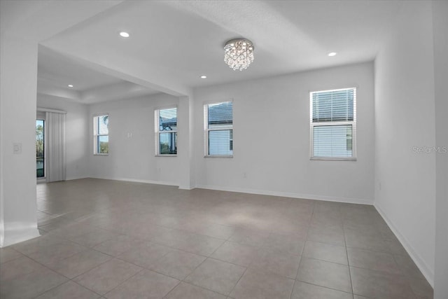 empty room with light tile patterned floors, a chandelier, recessed lighting, baseboards, and a tray ceiling