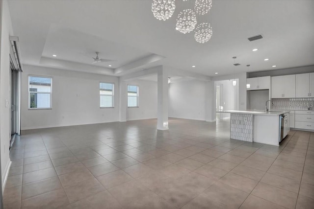 interior space featuring light tile patterned floors, open floor plan, decorative backsplash, and a raised ceiling