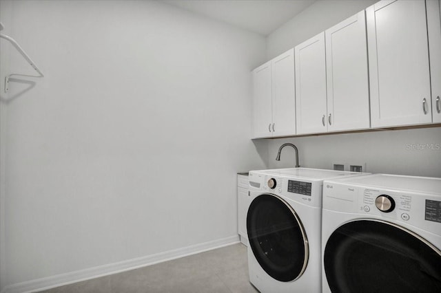 laundry room featuring baseboards, cabinet space, washing machine and clothes dryer, and light tile patterned floors