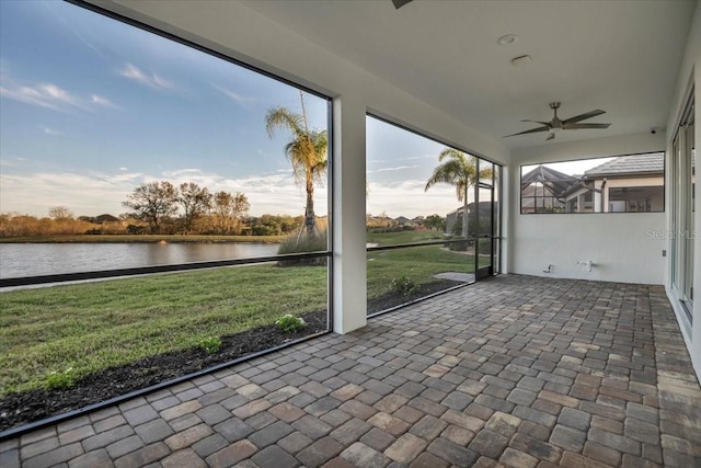 unfurnished sunroom featuring a water view and a ceiling fan