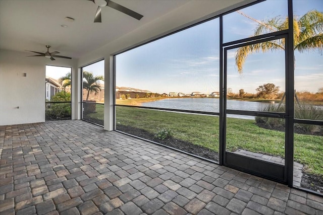 unfurnished sunroom featuring a water view and ceiling fan