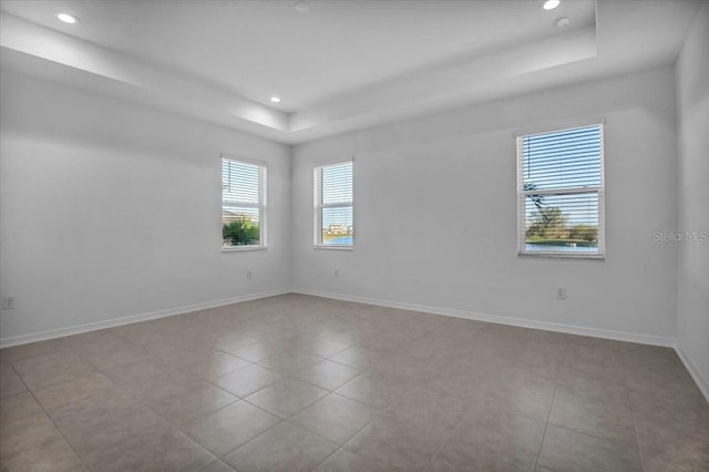 unfurnished room featuring a tray ceiling, recessed lighting, tile patterned floors, and baseboards