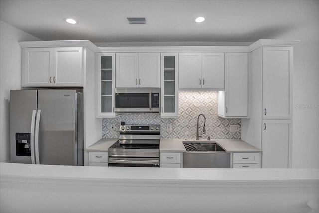 kitchen with light countertops, visible vents, backsplash, appliances with stainless steel finishes, and a sink