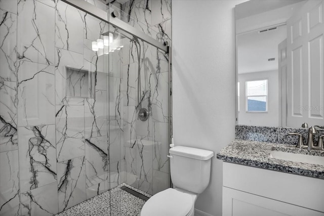 bathroom featuring toilet, a marble finish shower, visible vents, and vanity