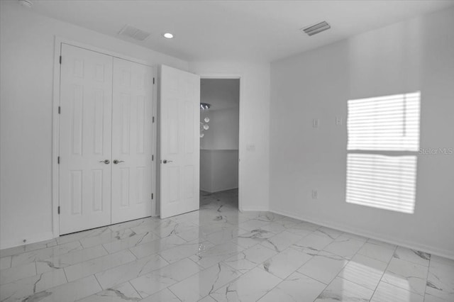 unfurnished bedroom featuring marble finish floor, baseboards, visible vents, and a closet