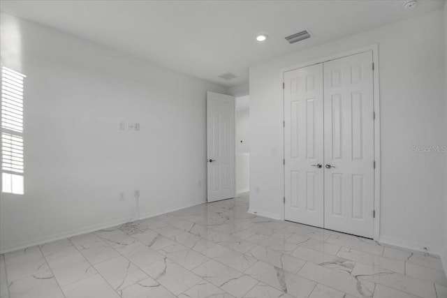 unfurnished bedroom with marble finish floor, baseboards, visible vents, and a closet